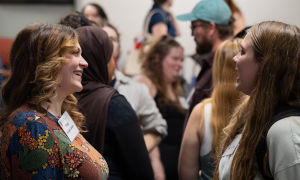 Two women speaking amongst a crowd of students