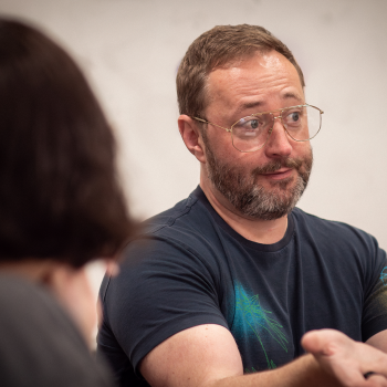 A man talks to a student in the foreground. 